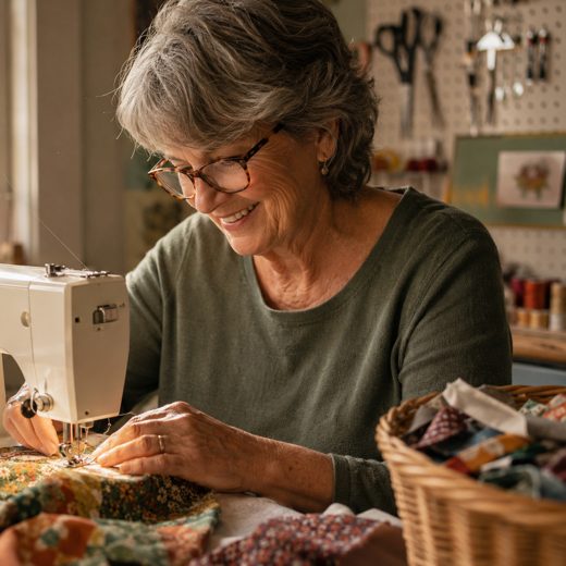 A sewist working at her machine in a sunlit sewing room